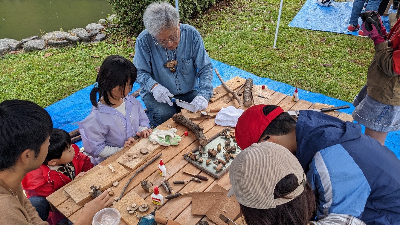 木の実や枝で作品をつくる子どもたちと達人